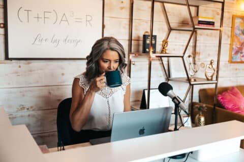 woman sitting at work desk sipping coffee